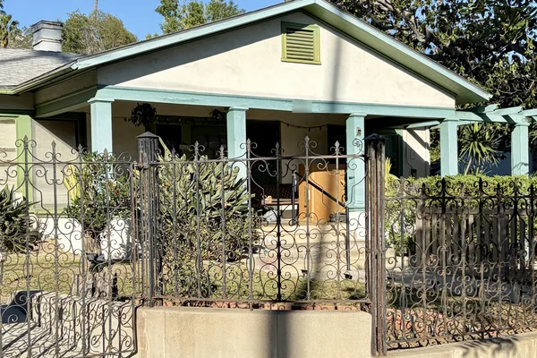 Bungalow on South Bel Aire Drive in Burbank behind a low concrete wall and iron fence