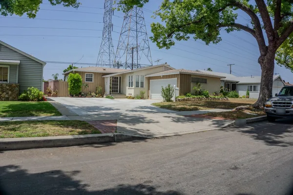 Wide concrete driveway and apron meeting the street curb in front of ranch houses
