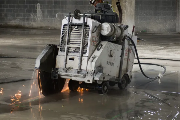 Worker running a walk-behind saw through an old concrete slab before it is broken out