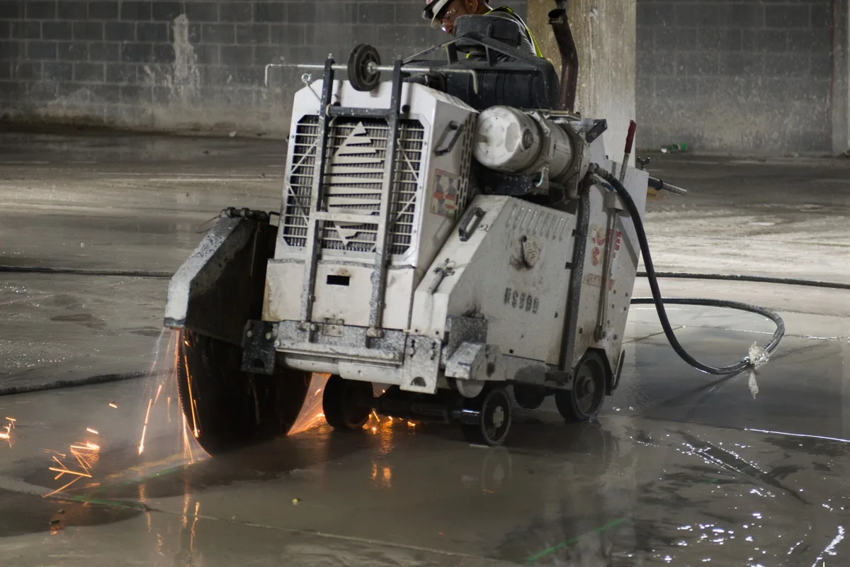 Worker running a walk-behind saw through an old concrete slab before it is broken out