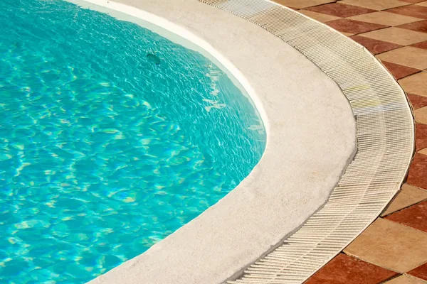 Curved pool edge with rounded coping and a tiled deck beyond it