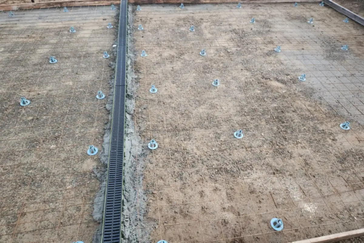 Steel reinforcement on plastic chairs and a channel drain set in a driveway before the pour