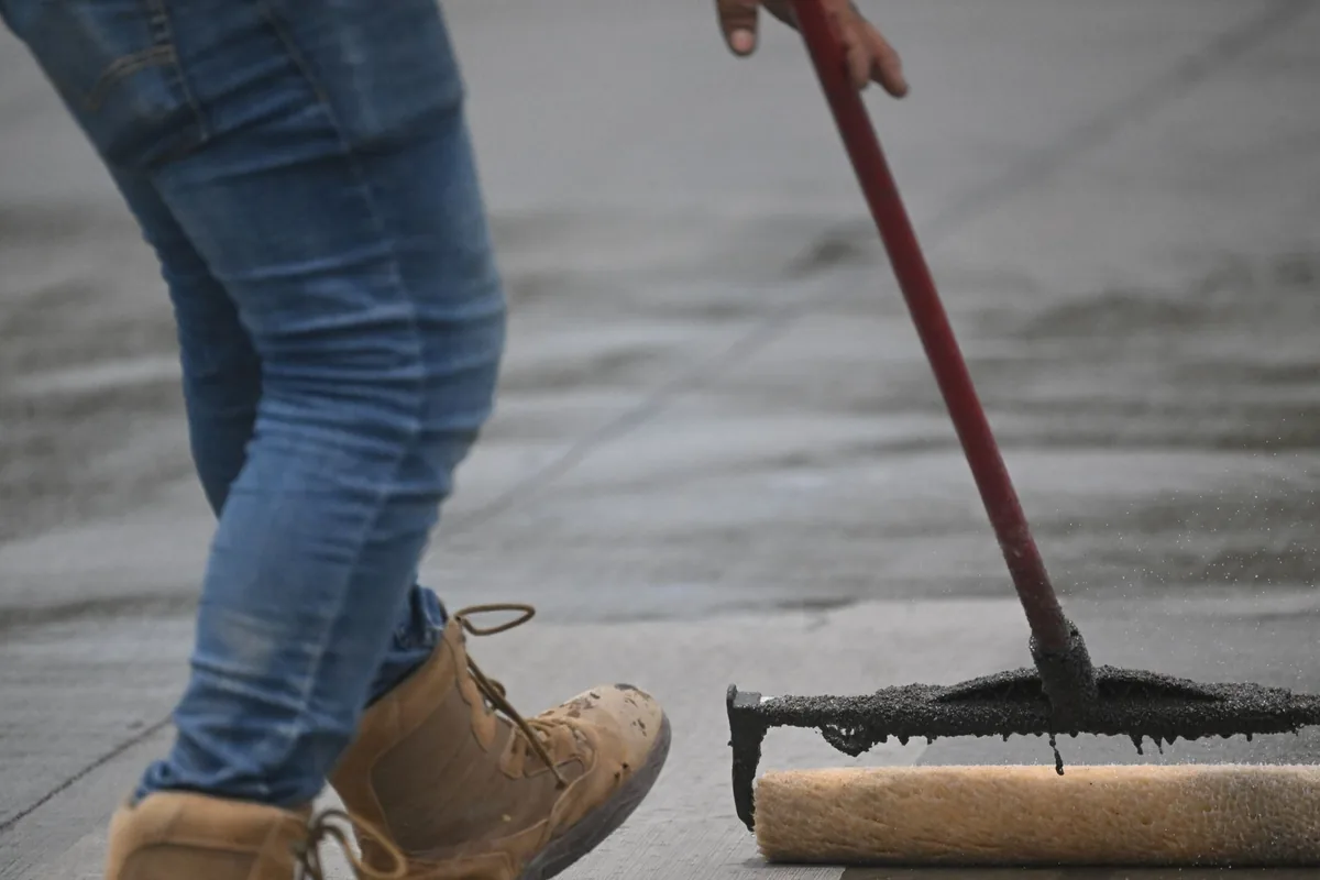 Worker spreading a coating over concrete with a squeegee