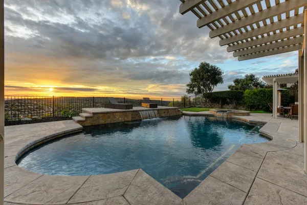 Stamped concrete pool deck under a pergola at sunset