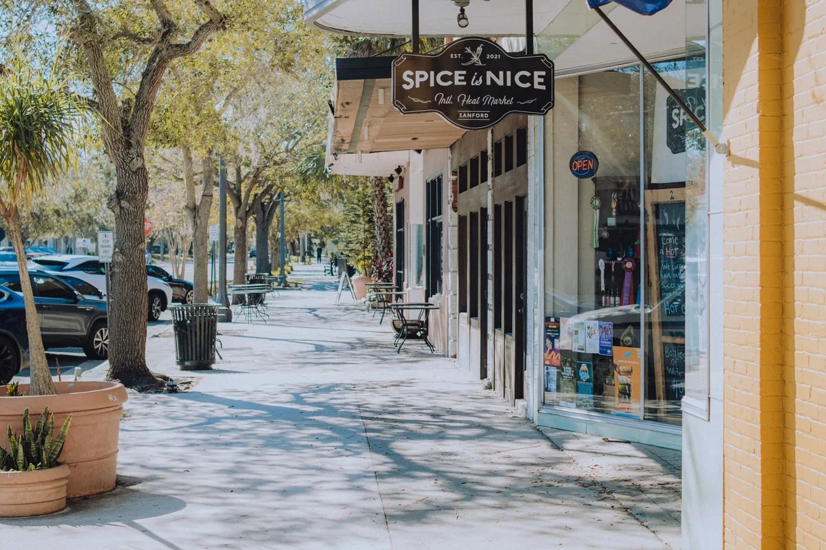 Sunny shopping street with a wide concrete sidewalk along the storefronts